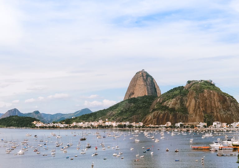 Sugarloaf Mountain in Rio de Janeiro with a view of the bay, dotted with numerous boats and surrounded by lush greenery.