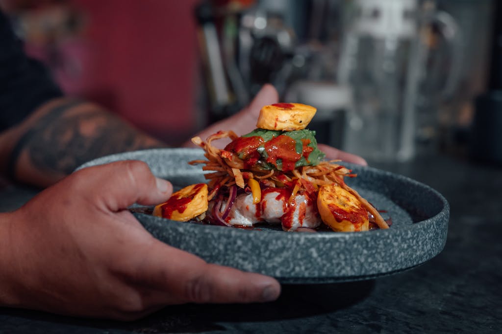 A person holding a plate of food with a fork