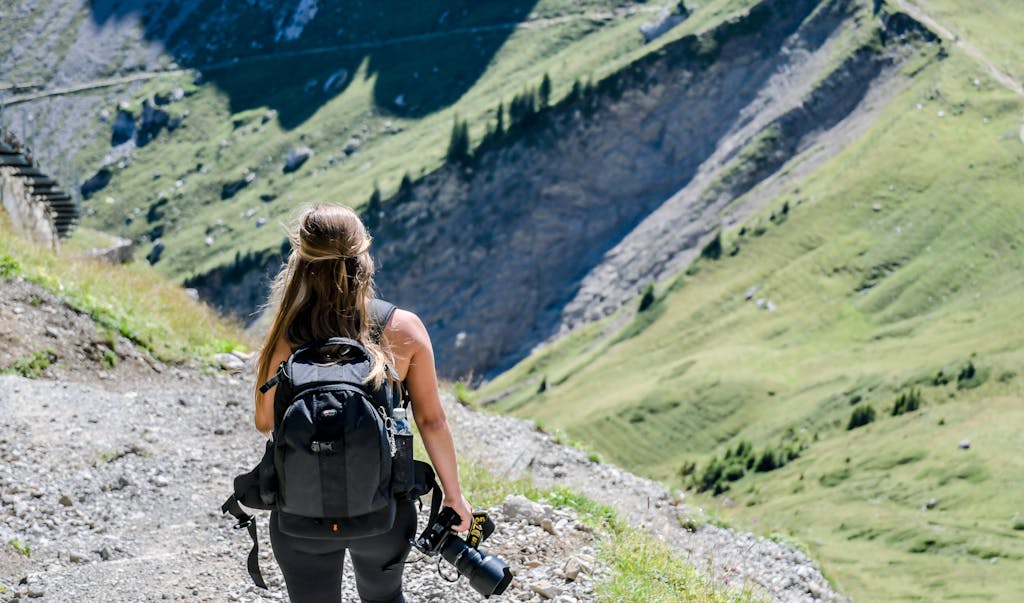 Woman Carrying Backpack While Holding a Camera