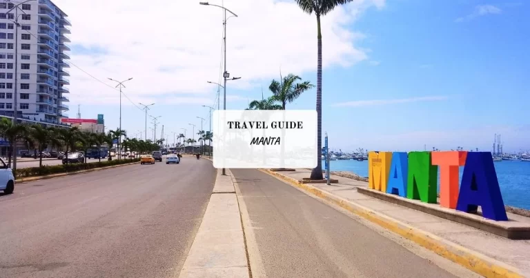 Road along a coastline with palm trees. Colorful "Manta" sign on the right, buildings on the left. Blue sky and parked cars visible. Text reading "Travel Guide - Manta" in the center.