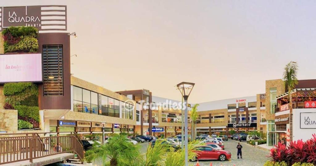 A shopping center with multiple stores and a spacious parking area. The building's facade features several vibrant signs, creating an inviting atmosphere for shoppers.