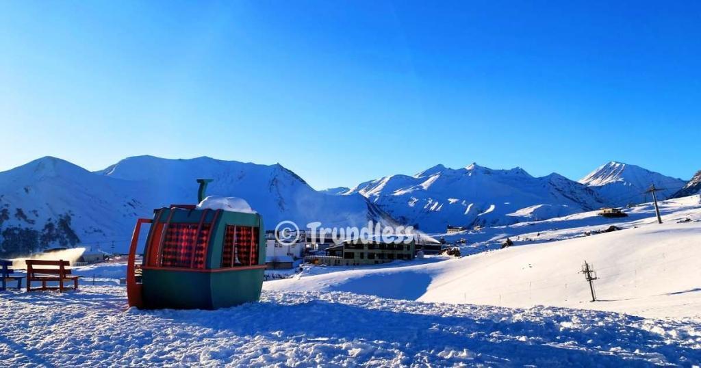 Snow-covered mountains and a ski lift in a winter landscape under a clear blue sky.